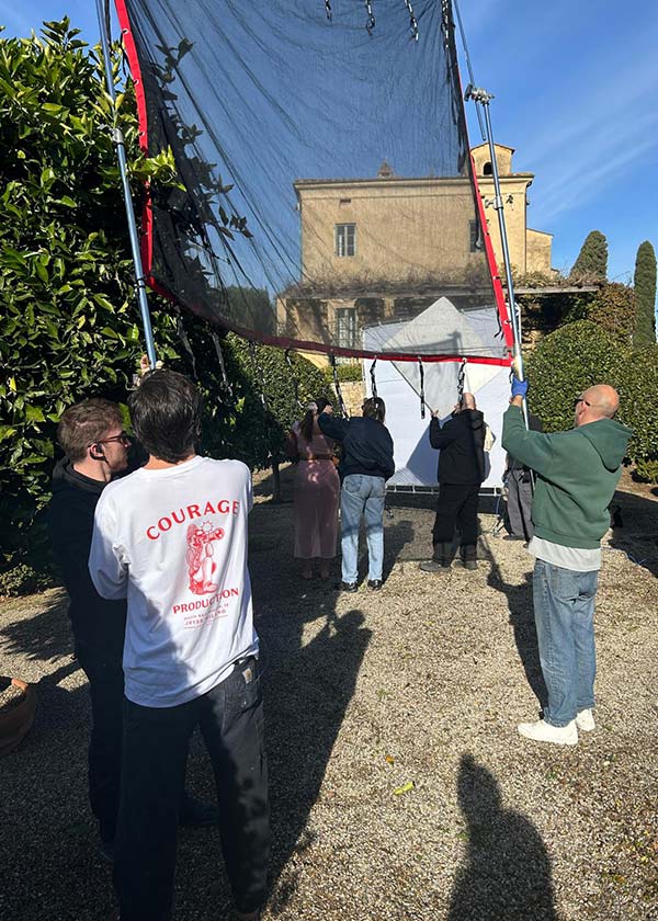 Fashion photography crew shooting inside a historic Tuscan villa, showcasing lighting setup and production logistics in a private heritage location